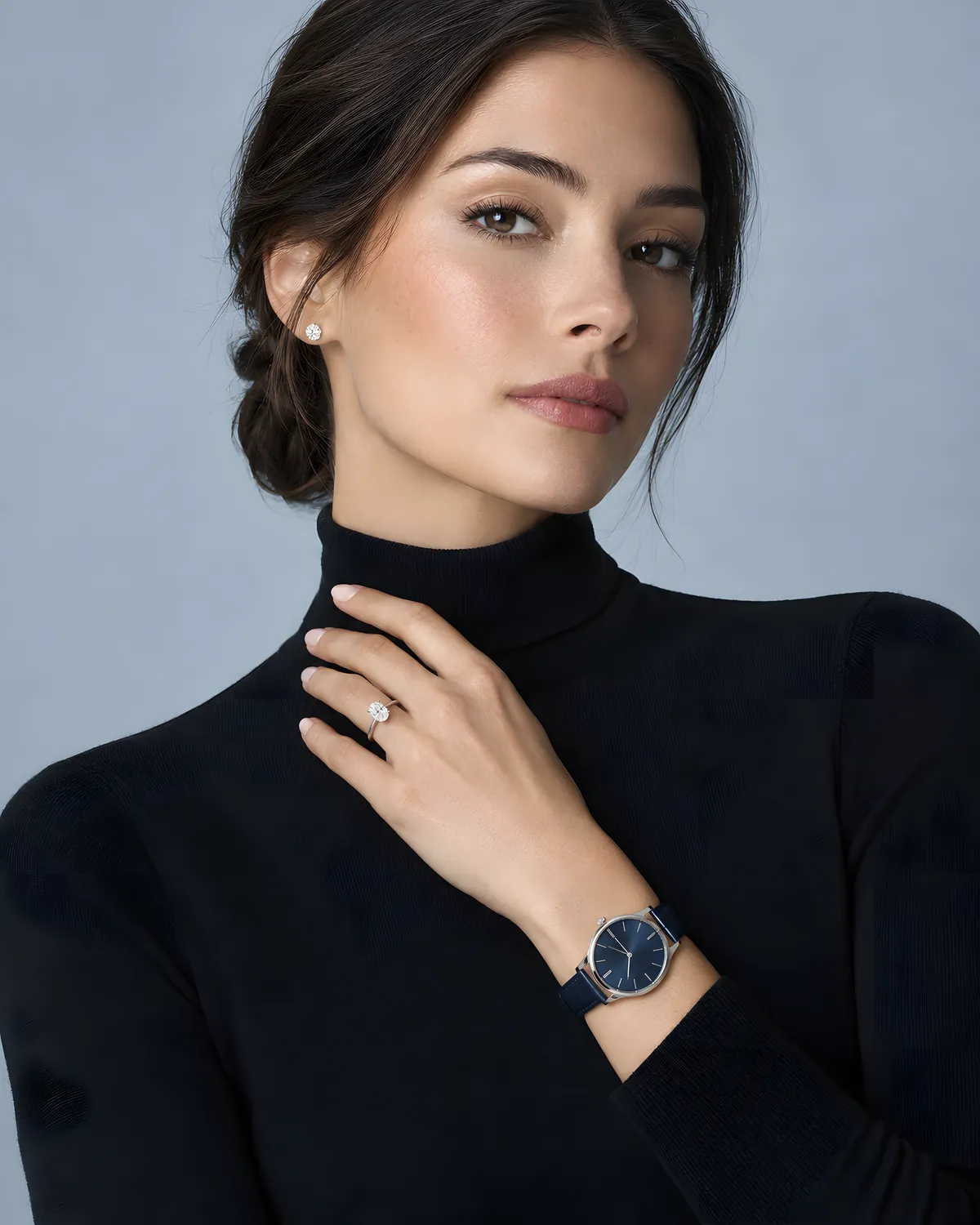 Woman in a black turtleneck wearing an oval diamond solitaire and a navy-dial watch
